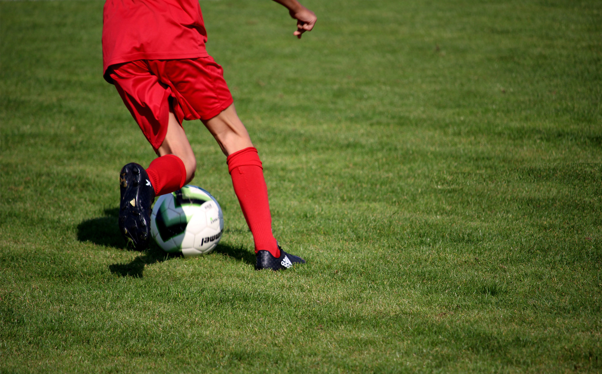 Junger Fussballer rennt mit Ball über Rasen